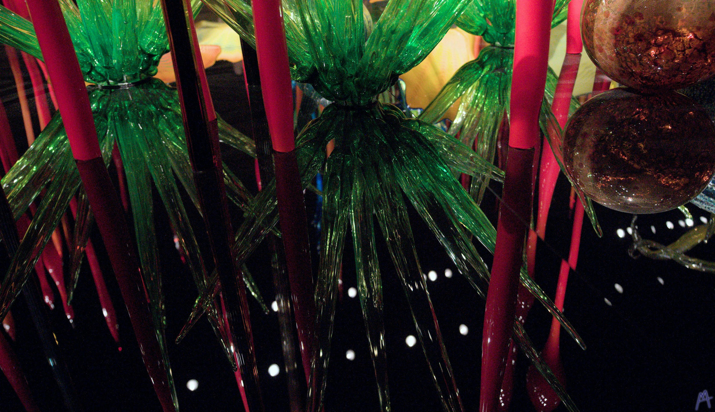 Green and red glass sculptures reflecting in the dark